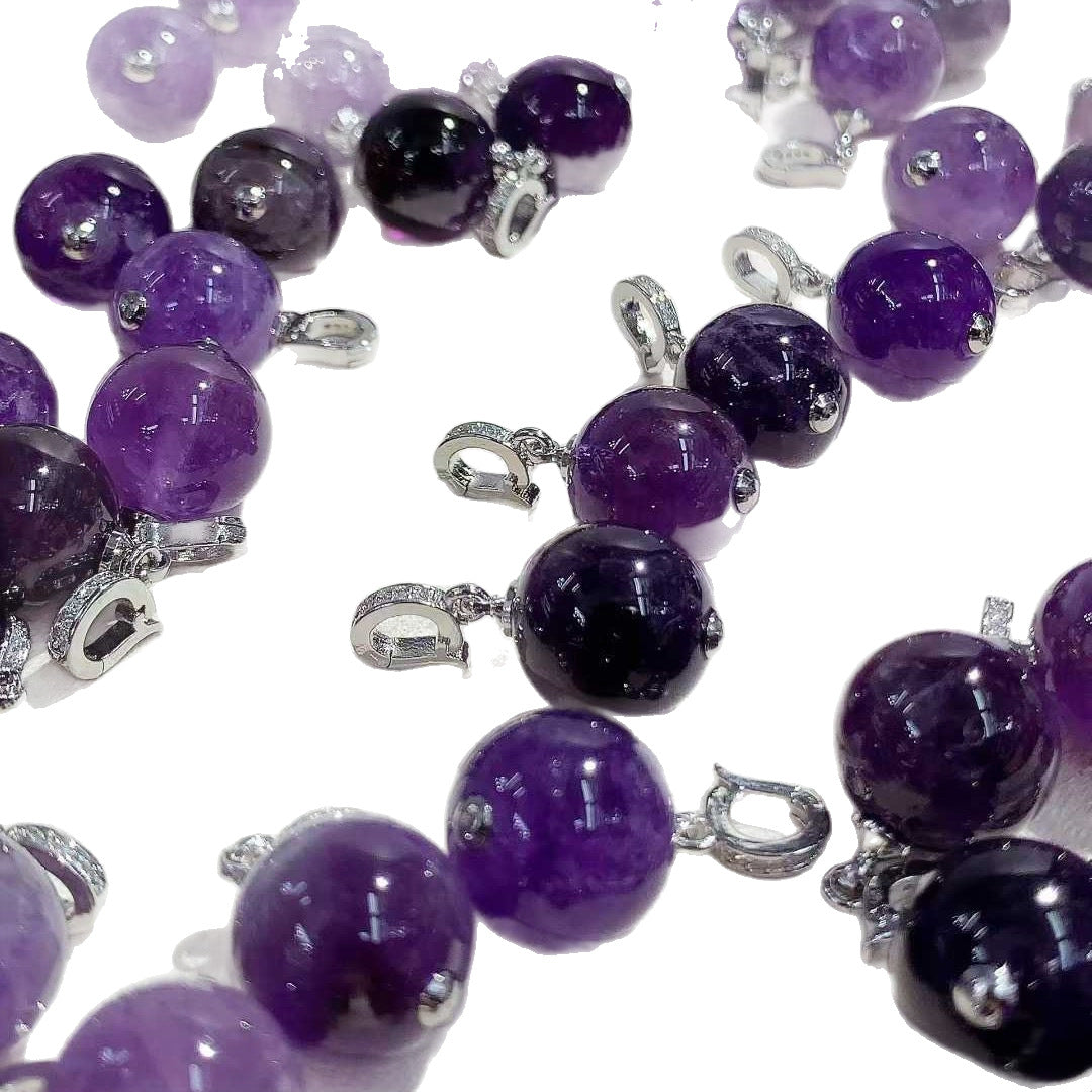 Collection of round purple pendants with silver-tone fittings on a white background